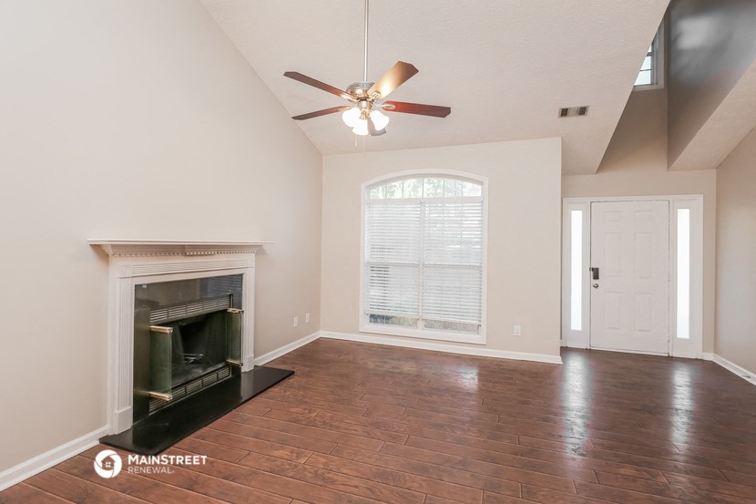 a living room with a fireplace and a ceiling fan