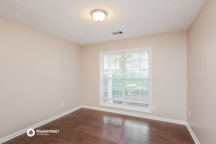 the spacious living room with a large window and wood flooring