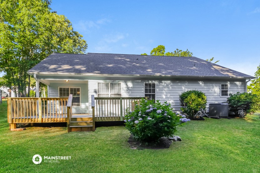 a small white house with a deck and a yard