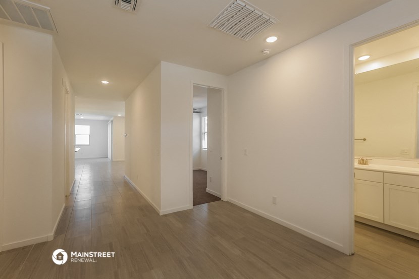 a renovated living room and hallway with white walls and wood flooring