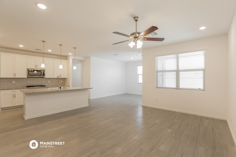 an empty living room and kitchen with a ceiling fan