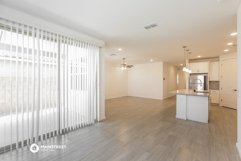 the living room and kitchen of an apartment with white blinds on the window