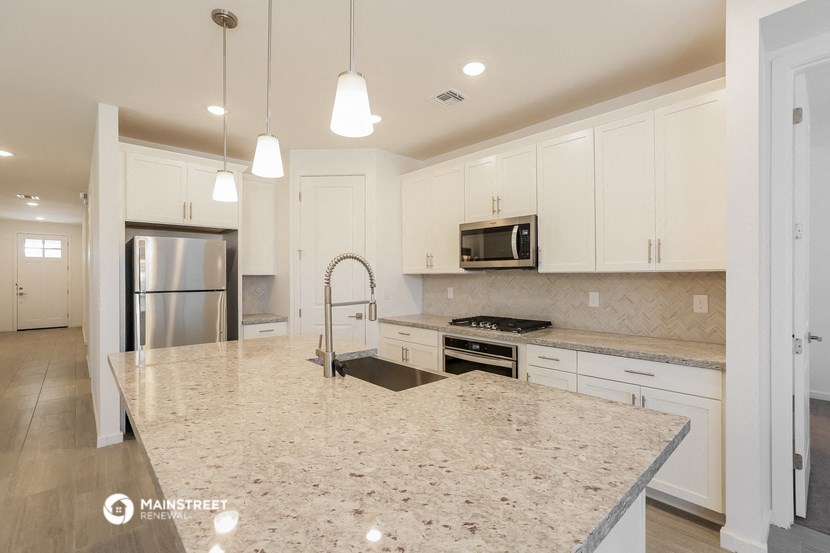 a kitchen with white cabinets and a marble counter top