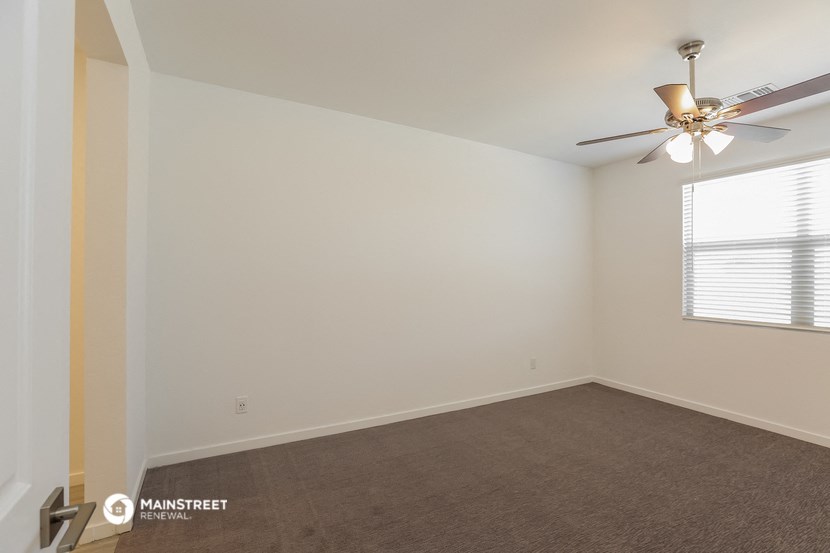 the living room of an empty house with a ceiling fan