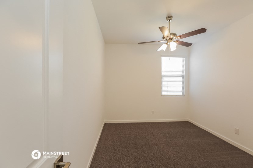 an empty room with a ceiling fan and a window