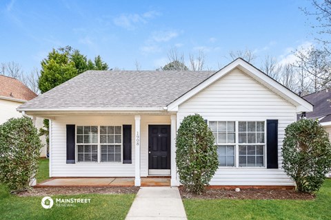 a small white house with a sidewalk in front of it