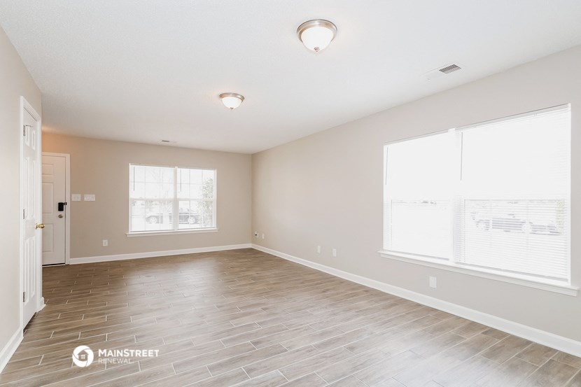 the spacious living room with wood flooring and two windows