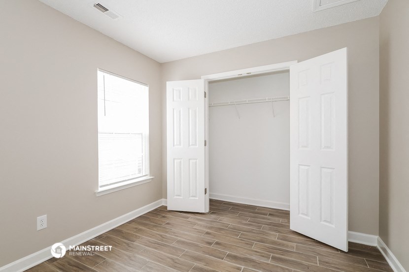 a bedroom with two closets and a door to a closet and a window