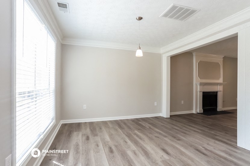 an empty living room with a fireplace and wood flooring