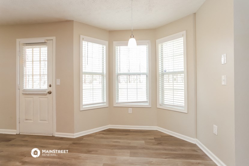 the spacious living room with a white door and windows
