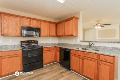 a kitchen with wood cabinets and black appliances and granite counter tops