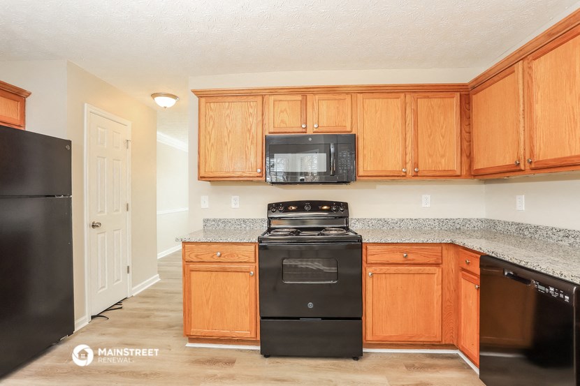 a kitchen with wood cabinets and black appliances and granite counter tops