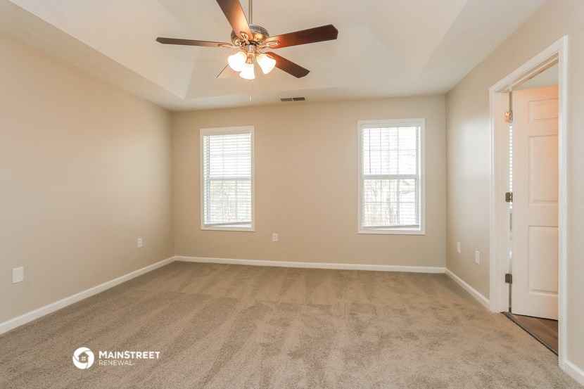 the spacious living room with carpeting and a ceiling fan