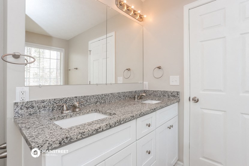 a bathroom with white cabinets and granite counter top and a sink