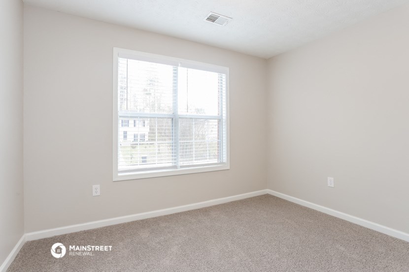 a bedroom with a large window and carpeting