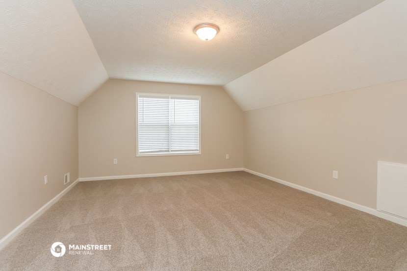 the spacious living room with carpeting and a window