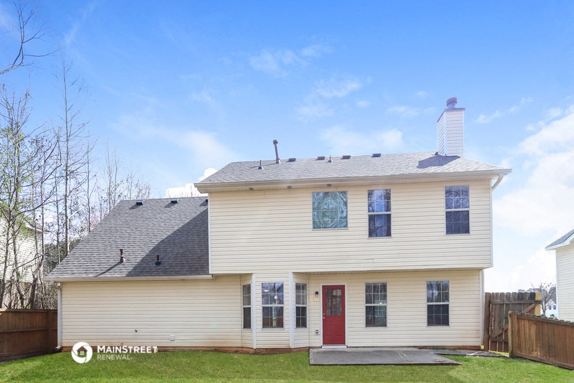 the front of a white house with a red door