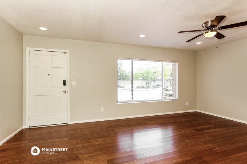 an empty living room with a window and a ceiling fan