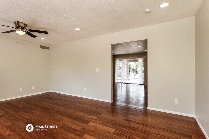 an empty living room with wood floors and a ceiling fan