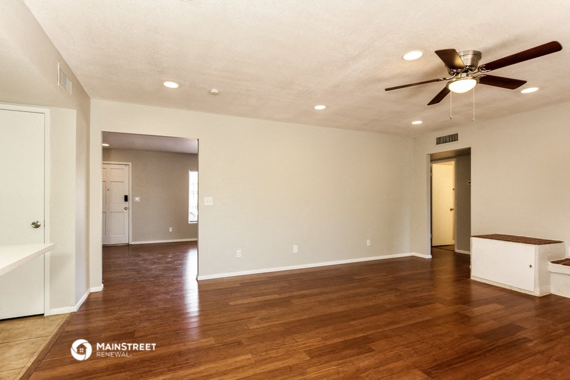 an empty living room with wood floors and a ceiling fan