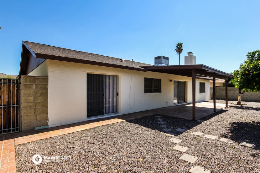 a small white house with a driveway and a palm tree
