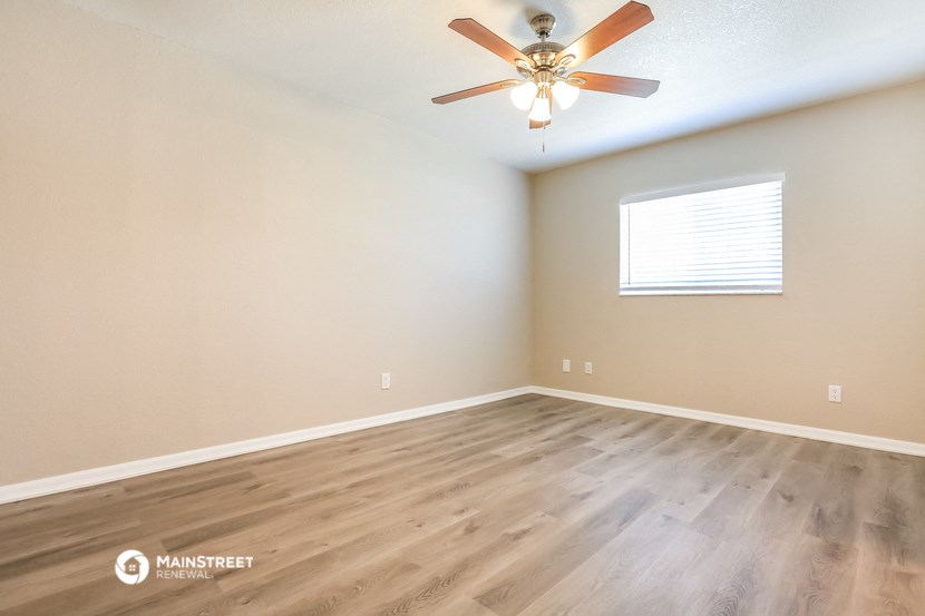 the spacious living room with hardwood floors and a ceiling fan