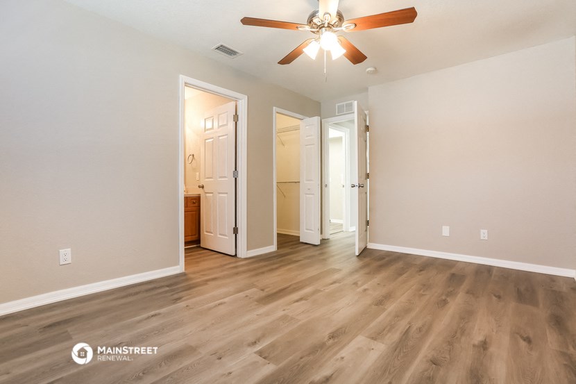 the living room of an apartment with wood flooring and a ceiling fan
