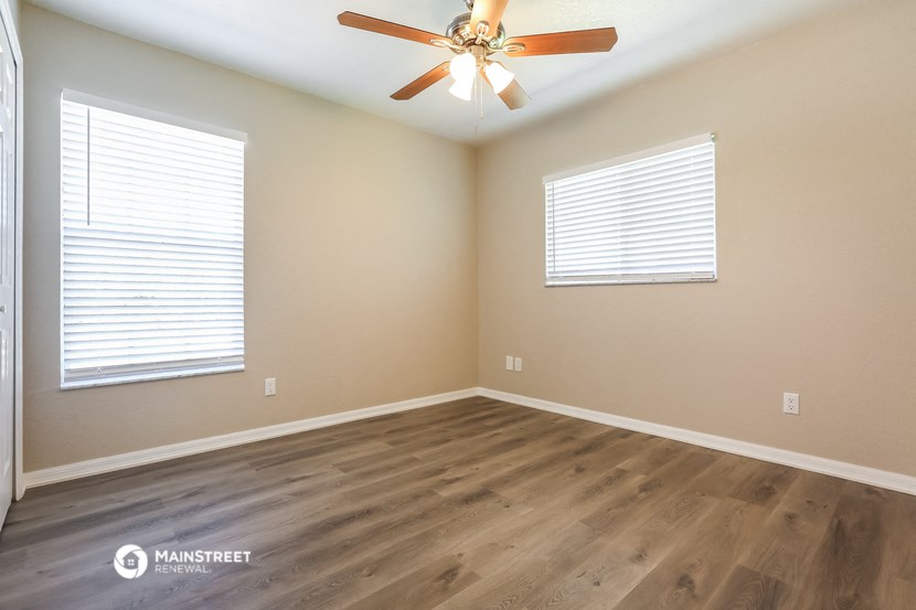 the spacious living room with hardwood floors and a ceiling fan