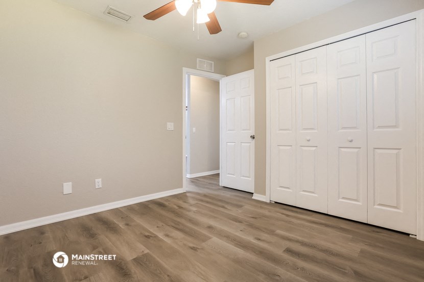 the spacious living room with white doors and a ceiling fan