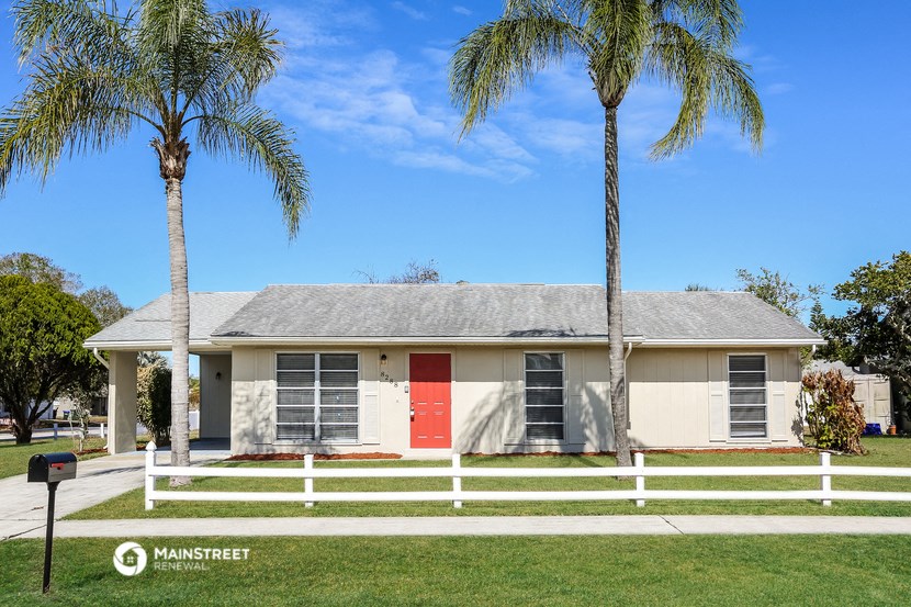 a white house with a red door and two palm trees