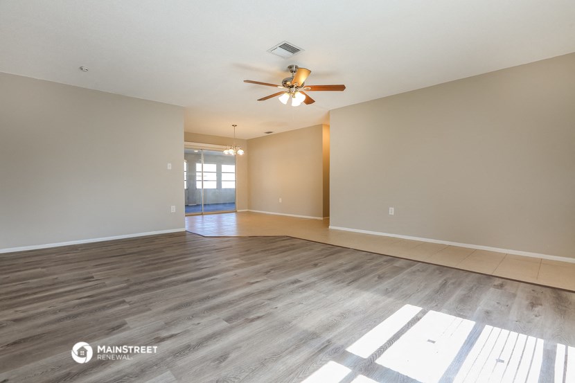 the spacious living room with wood flooring and ceiling fan