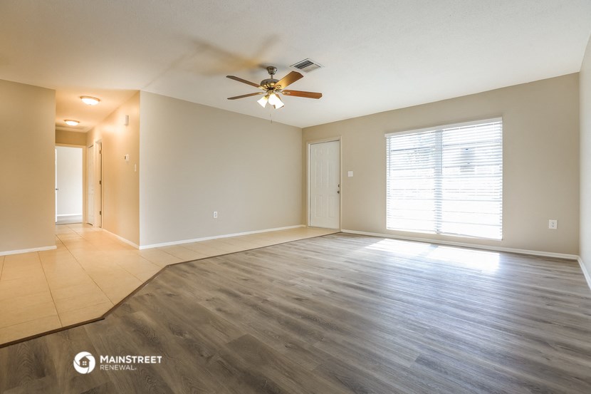 an empty living room with a ceiling fan and a large window