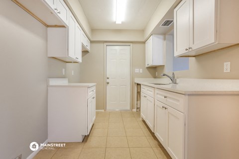 a kitchen with white cabinets and counters and a white door