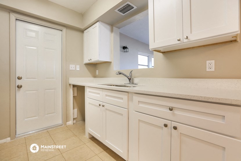 a kitchen with white cabinets and a sink and a door