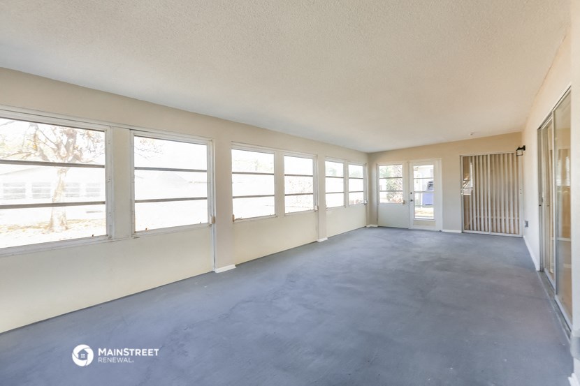 a spacious living room with large windows and a concrete floor