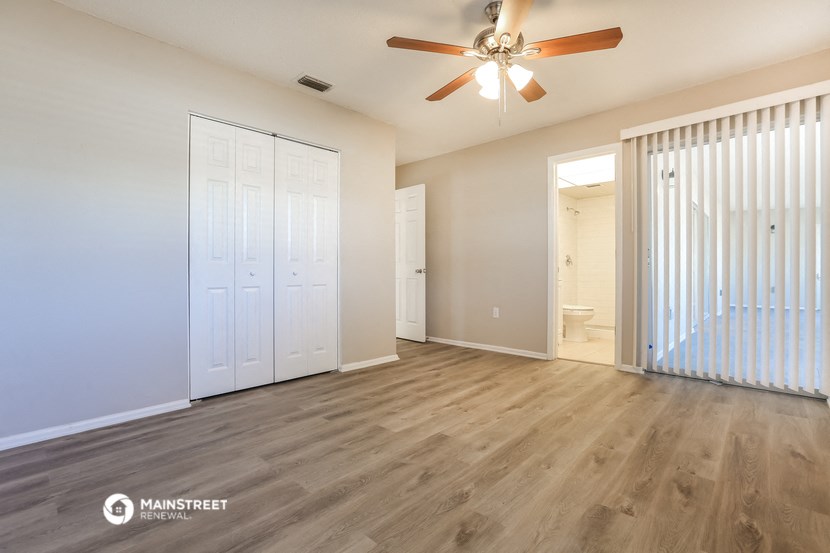 a living room with a ceiling fan and a door to a bathroom