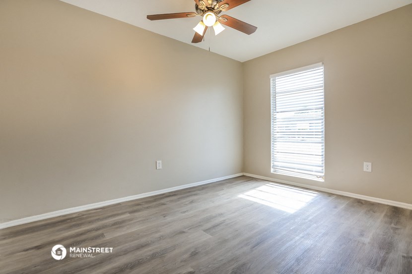 an empty living room with wood floors and a ceiling fan