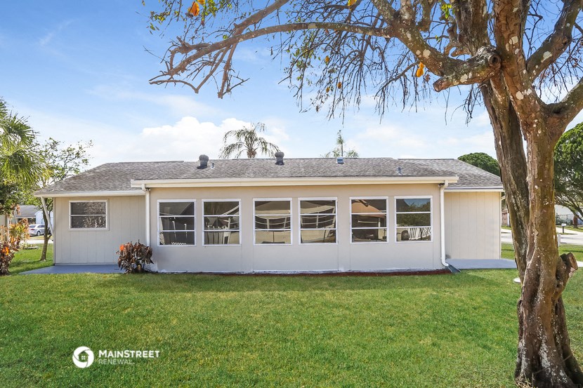 a white house with a lawn and a tree