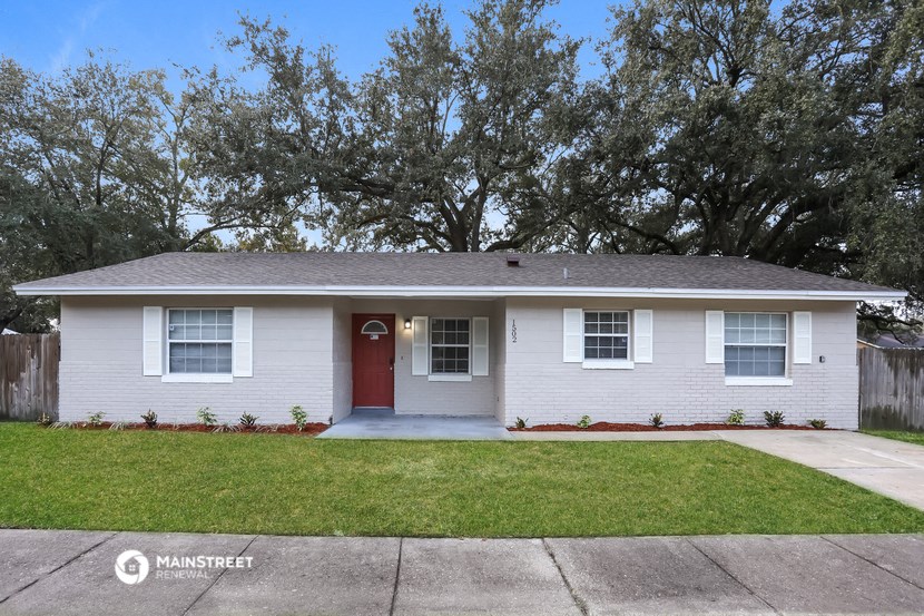 a white house with a red door and a lawn