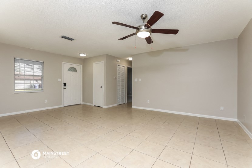 the spacious living room with ceiling fan and tiled floor