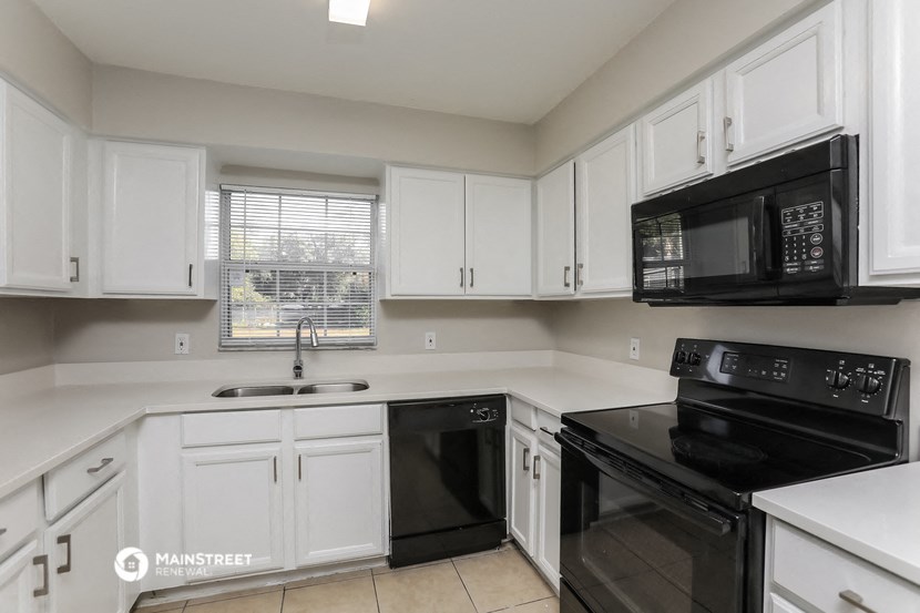 a kitchen with white cabinets and black appliances