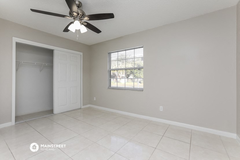 an empty living room with a ceiling fan and a closet