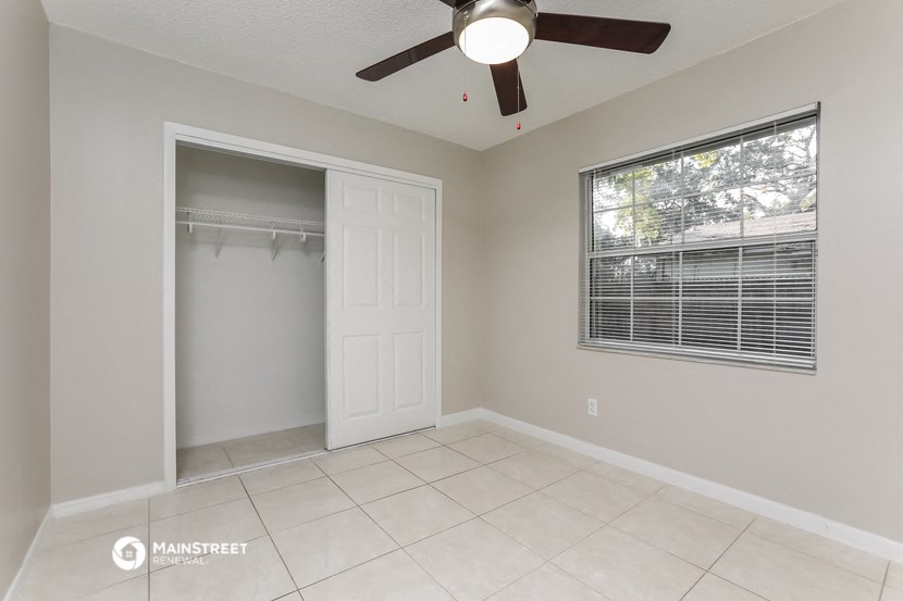 the spacious living room with a closet and a ceiling fan