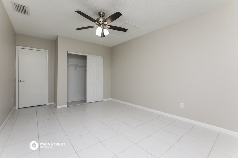 a empty living room with a ceiling fan and a closet