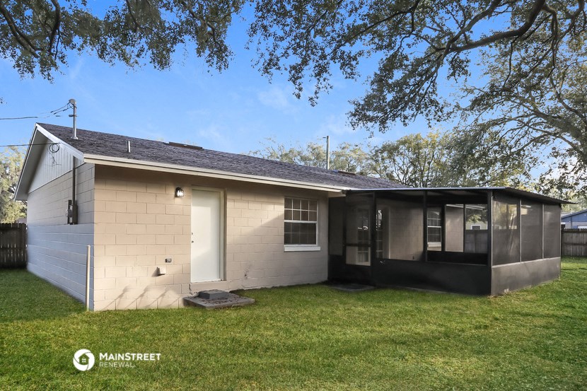 the exterior of a small house with a yard and a tree