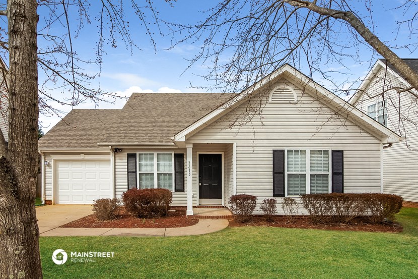 the front of a white house with a lawn and trees