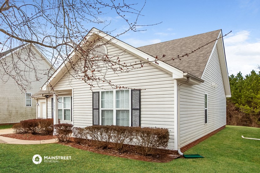 a white house with a lawn and a tree