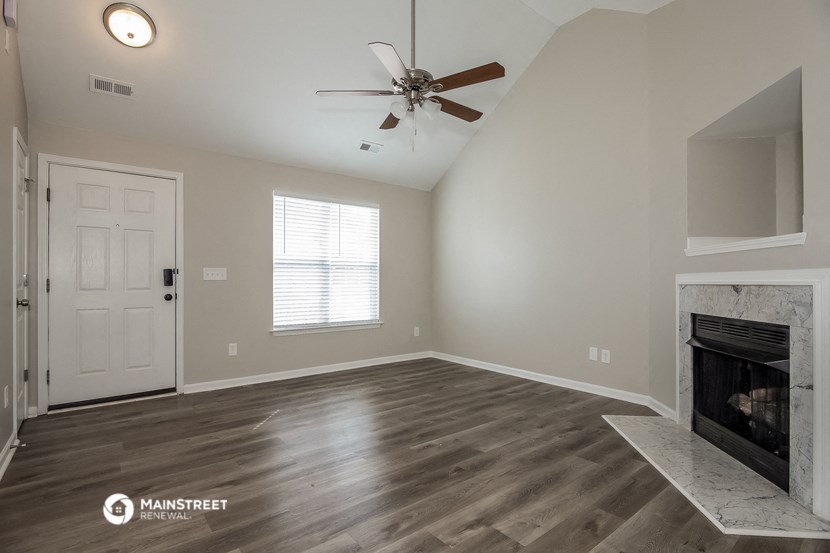 the living room with a fireplace and a ceiling fan