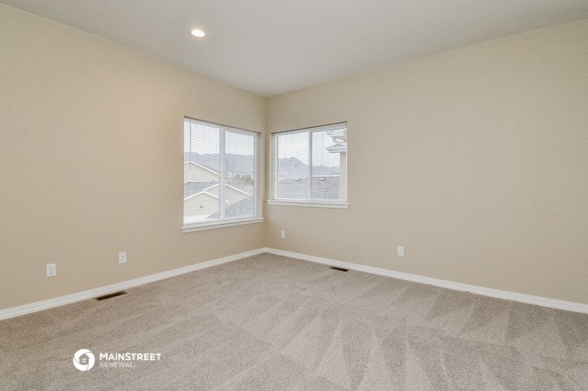 an empty living room with two windows and carpeting