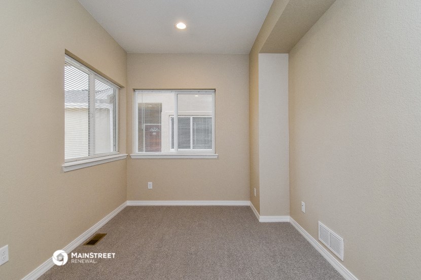 an empty living room with two windows and a carpet